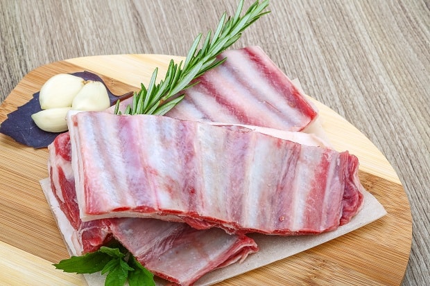 две сырые бараньи корейки с чесноком и зеленью