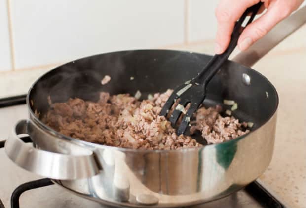 обжаренный фарш с шумовкой в сотейнике на плите