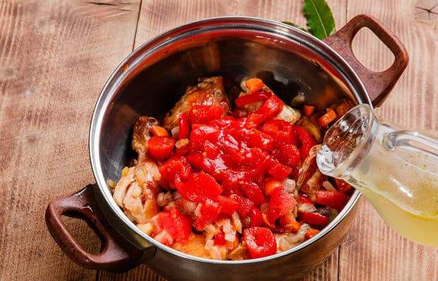 кусочки помидоров с курицей в кастрюле заливаются бульном