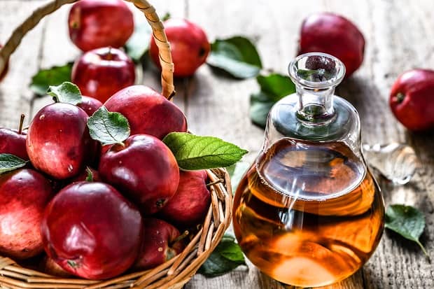 яблочный уксус в графине и яблоки в корзинке