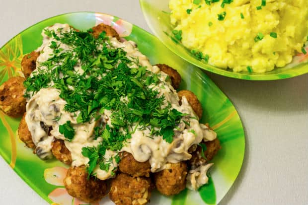 жареные фрикадельки с соусом и зеленью на тарелке
