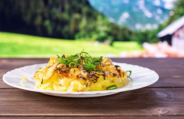 картофель, запеченный с луком и зеленью, на тарелке