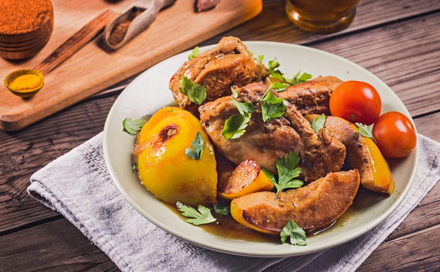 тушеная курица с айвой и зеленью на тарелке