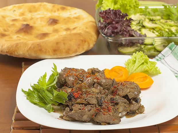 тушеная куриная печень с овощами на тарелке, лаваш и зелень
